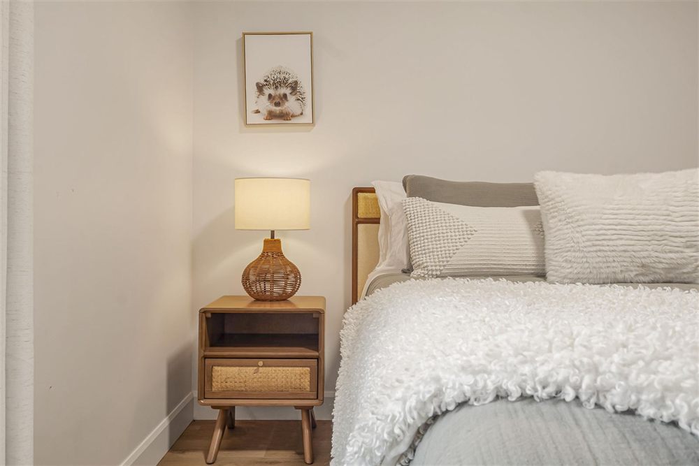 Chambre avec literie texturée et table de chevet en rotin