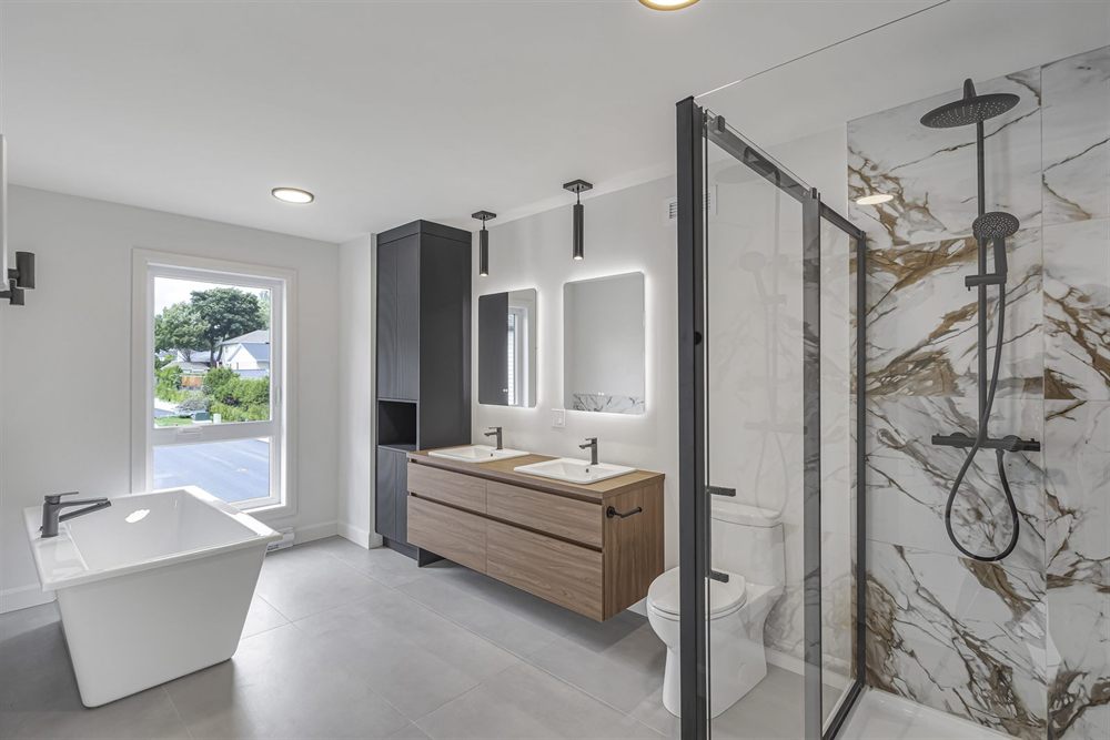 Salle de bain d'une maison neuve : bain autoportant, vanité double en bois et douche en marbre