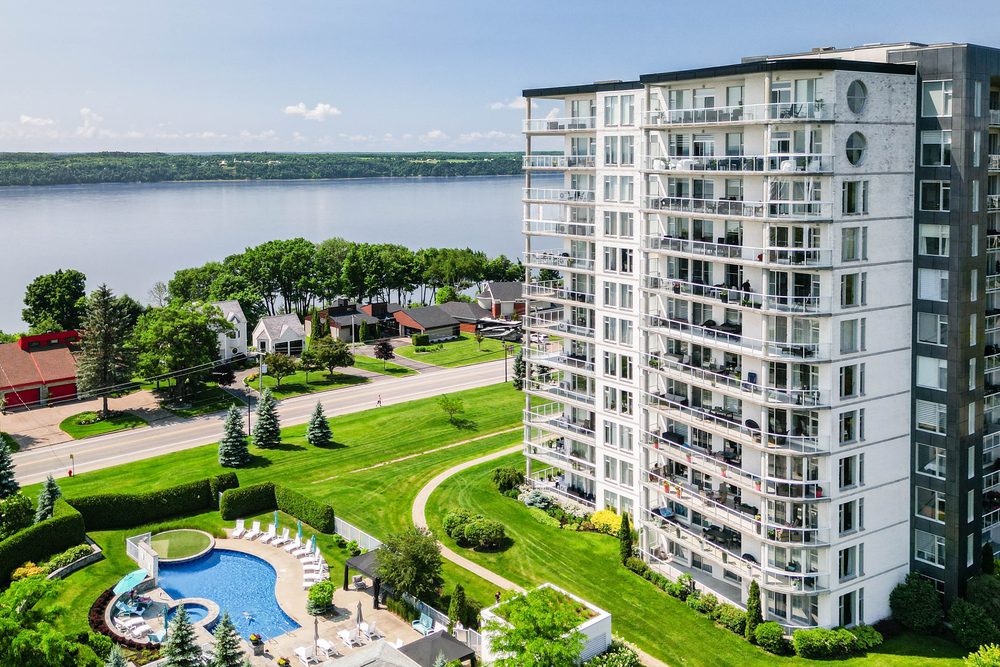 Vue aérienne d'un immeuble à condos en bordure du fleuve avec piscine extérieure