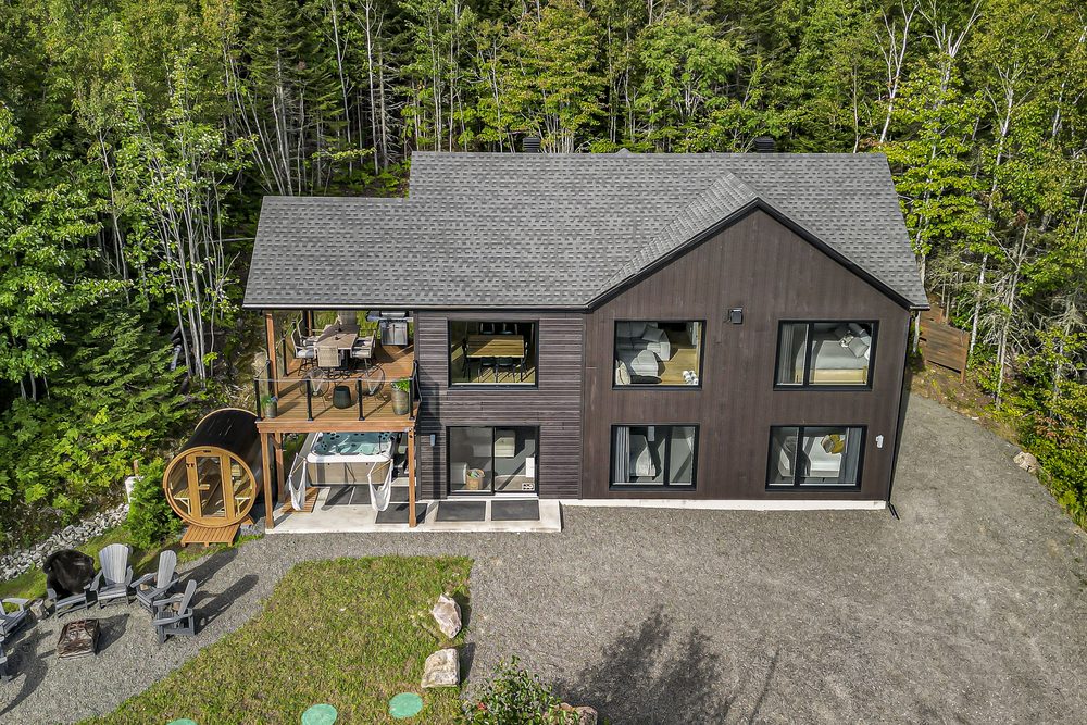 Vue aérienne d'un chalet contemporain en forêt avec spa, sauna et terrasse