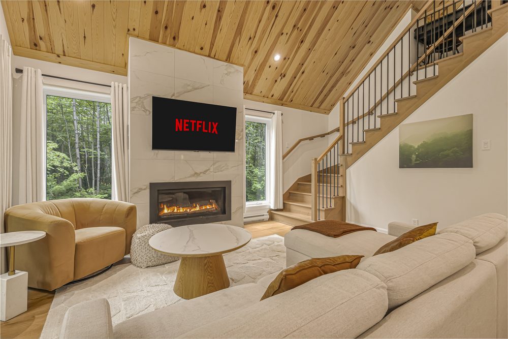 Salon de chalet avec foyer au gaz, télévision murale et plafond cathédrale en bois