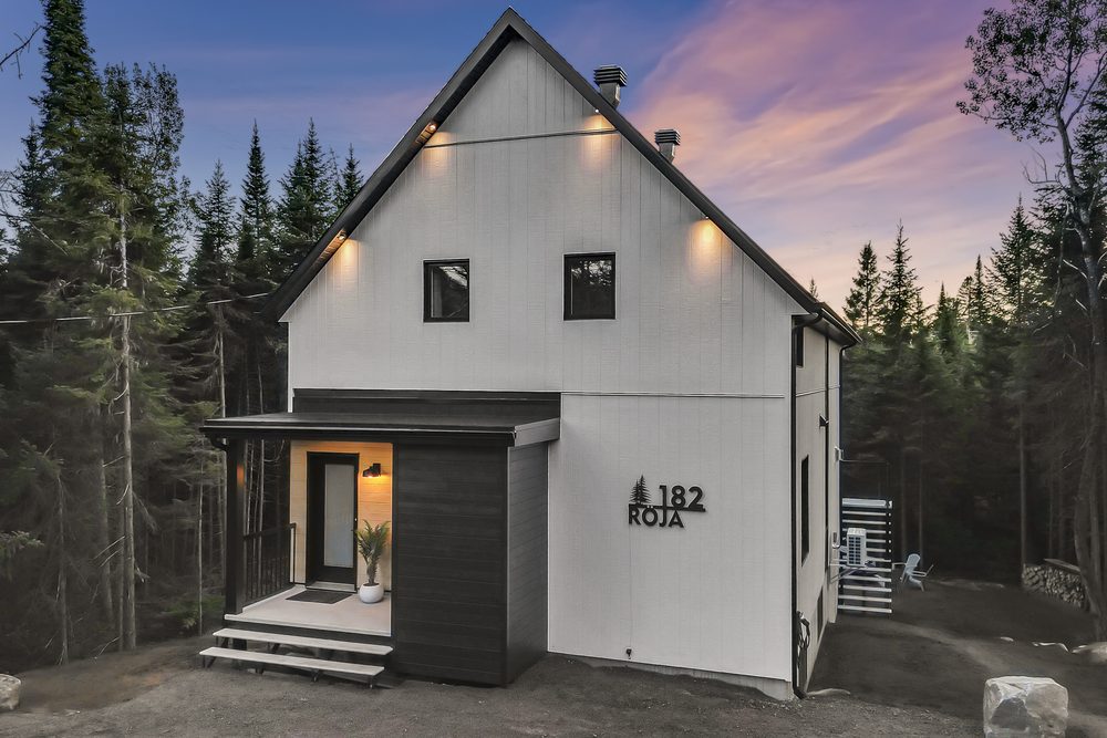 Façade d'un chalet contemporain en forêt, éclairée au crépuscule